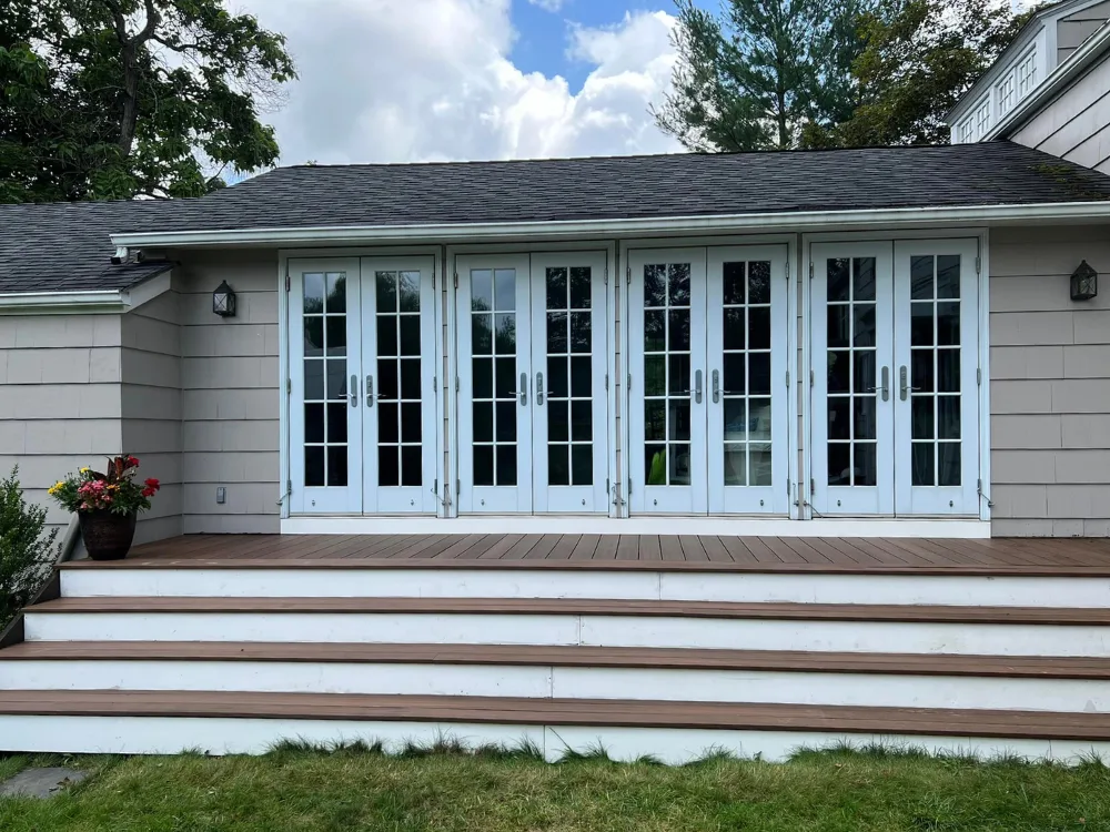 Brazilian Ipê deck renovation with NewTechWood composite boards and white stair risers in front of French doors.
