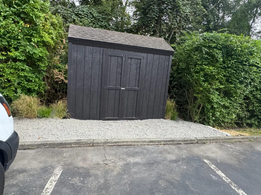 Completed wood shed restoration with dark exterior finish and new doors.